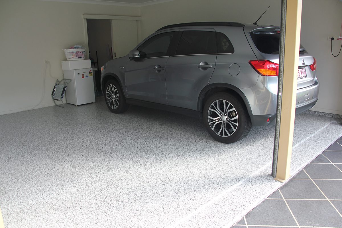 The front of the residential garage with doors open, showing the new epoxy flake floor with car parked on top of it.