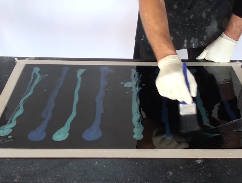 An installer applying a metallic epoxy design onto a sampleboard.