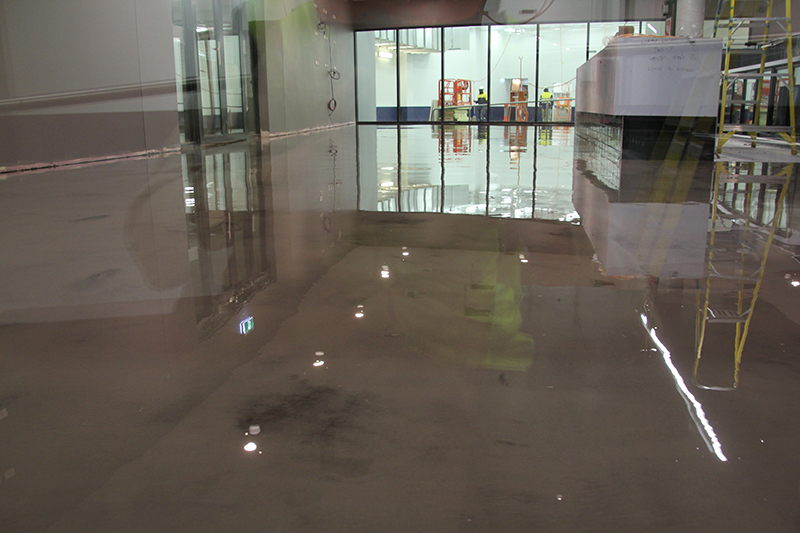 An epoxy metallic floor installation with other trades working next door.